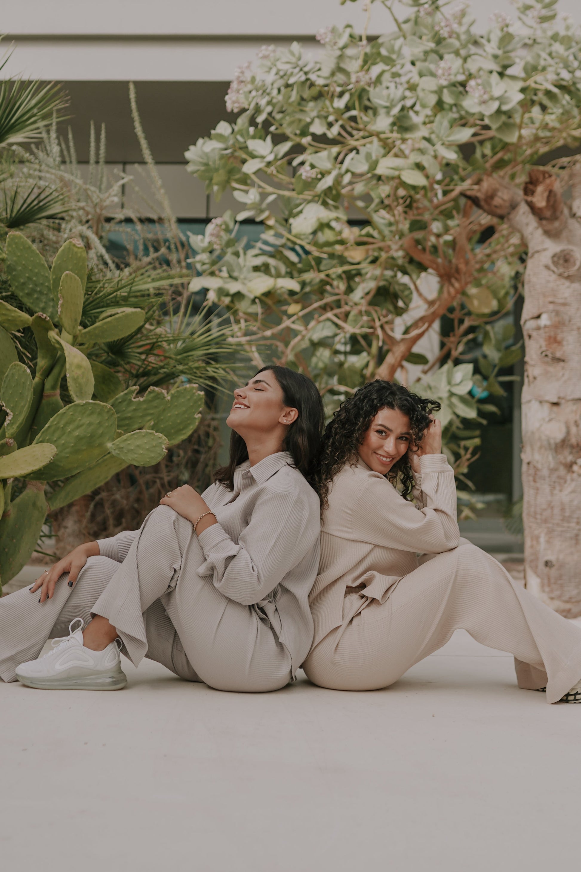 2 girls sitting back to back in off white loungewear